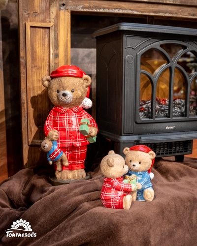 Figurines d'ours en pyjamas à carreaux rouges devant une cheminée.